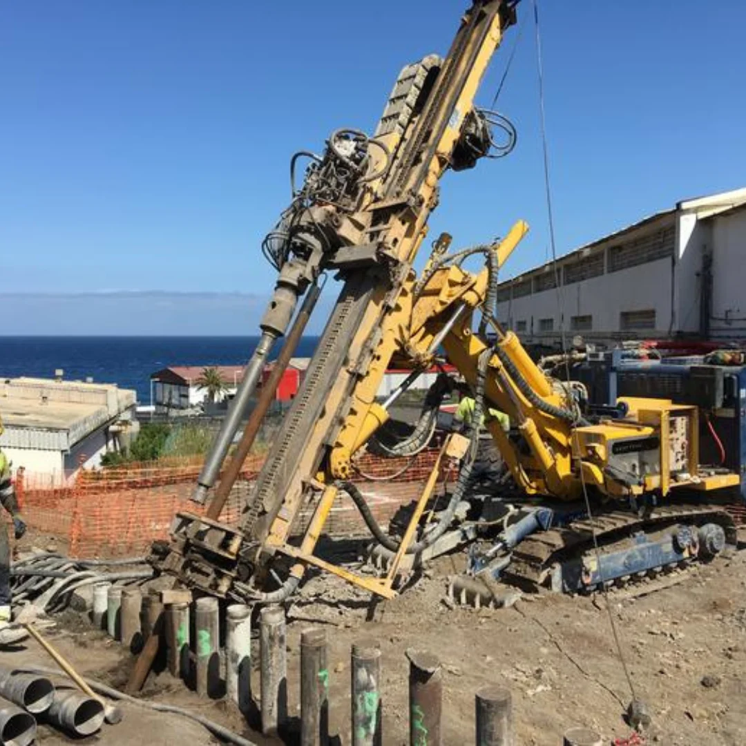 Perforadora compacta COMACCHIO MC12 ejecutando micropilote en obra con espacio limitado y operario con EPP