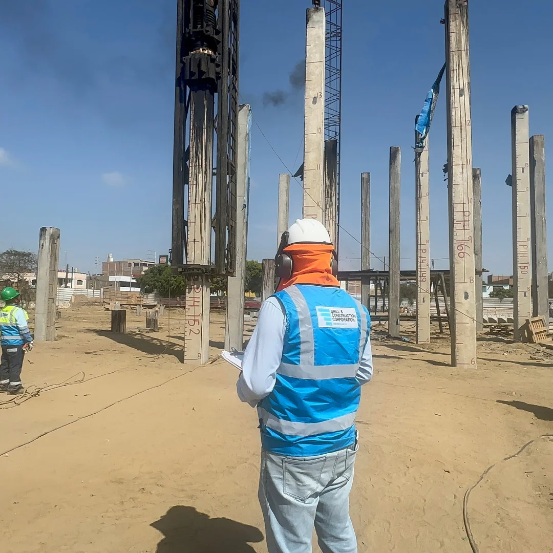 Pilotes prefabricados hincados por percusión en obra del Colegio Politécnico del Santa en Chimbote, ingeniero DCC con chaleco corporativo supervisando