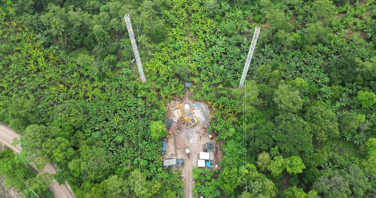 Vista aérea de la faja de una línea de alta tensión abierta en la selva, con dos torres y la plataforma de trabajo habilitada entre la vegetación