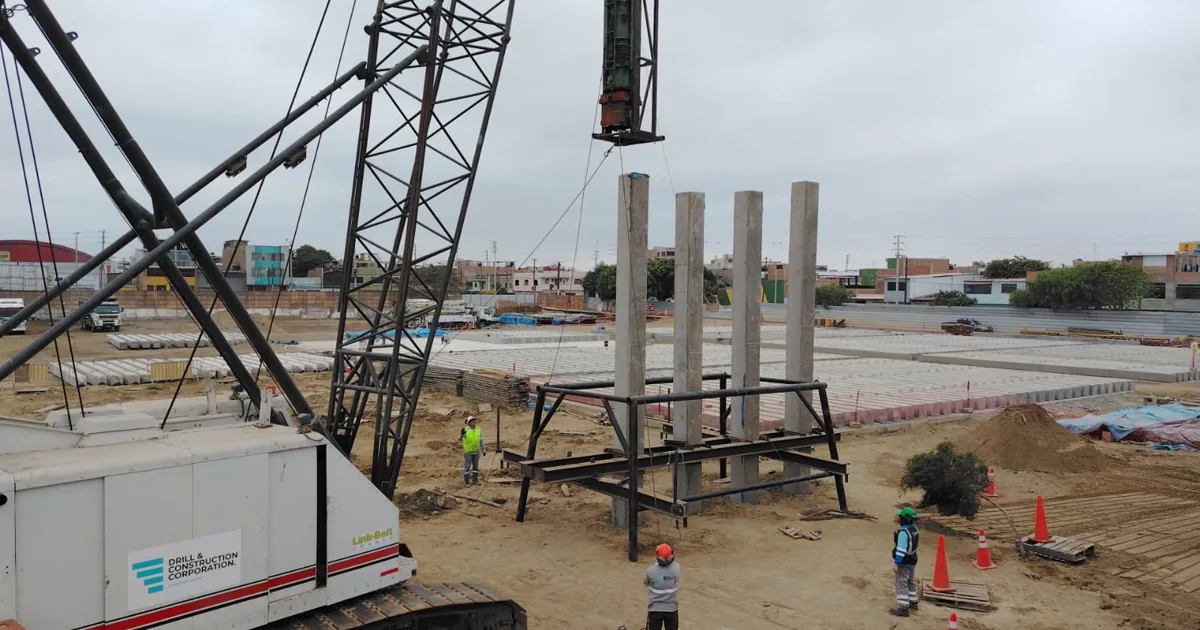 Grúa de orugas con el marco de hincado y pilotes prefabricados de concreto ya hincados en fila en el Colegio Politécnico del Santa