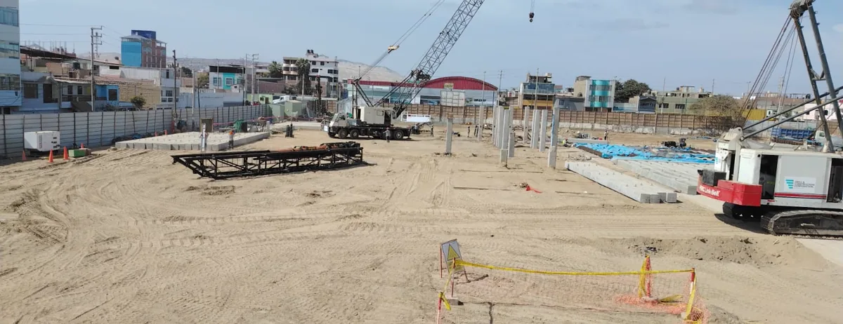 Vista general de la obra del Colegio Politécnico del Santa en Chimbote, con dos grúas de orugas y los marcos de hincado sobre la plataforma de trabajo
