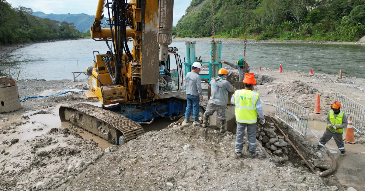 Equipo de perforación y personal de obra ejecutando pilotes excavados en la orilla del río Huallaga, Puente Muyuna