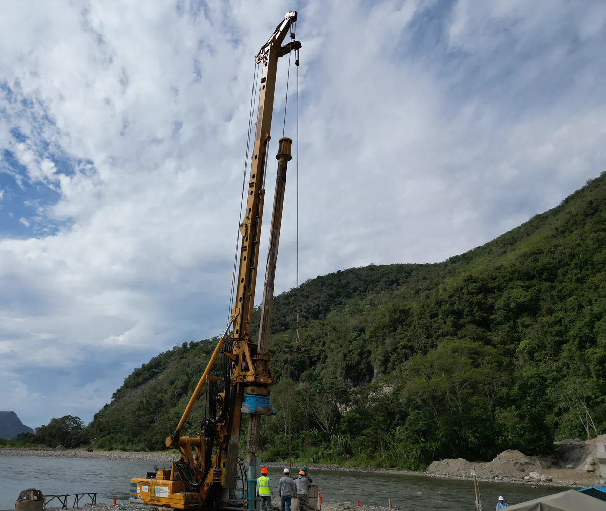 Equipo de perforación de pilotes excavados y la cuadrilla al pie del mástil, en la margen del río Huallaga, Puente Muyuna, Huánuco