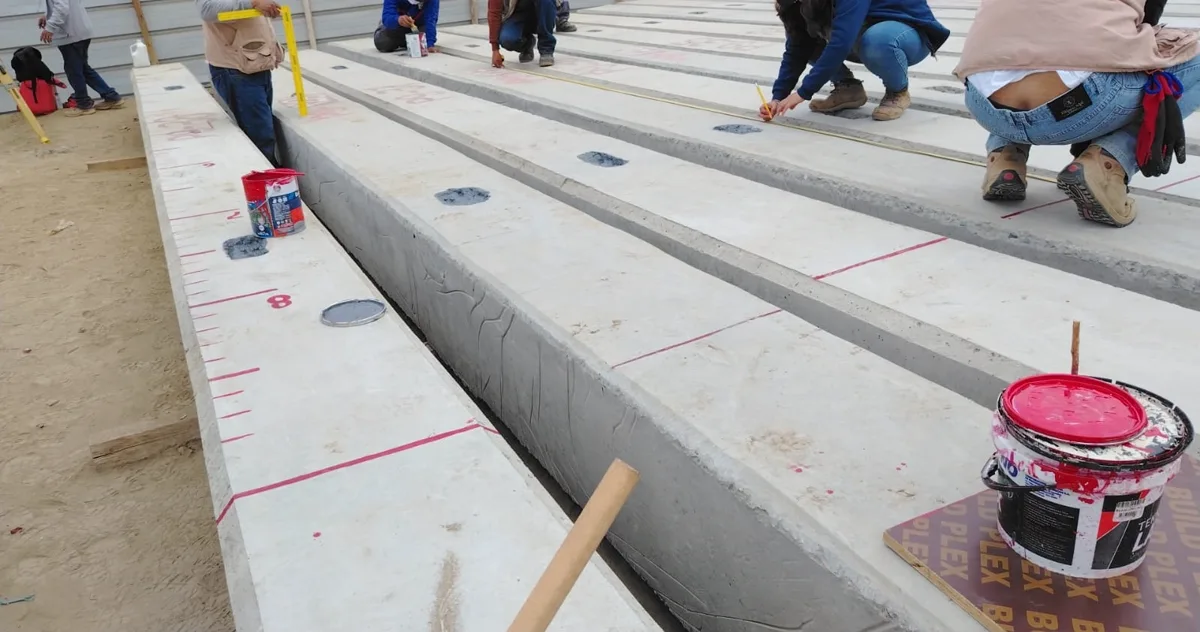 Pilotes prefabricados de concreto de sección cuadrada, acopiados en obra, con las marcas de graduación y los puntos de izaje mientras la cuadrilla los prepara